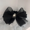 Dettaglio ravvicinato di un elastico per capelli con fiocco nero, perla e strass lucidi - Nero