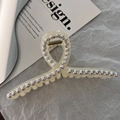 Dettaglio della molletta per capelli bianco crema con perle e strass su carta grigia - Incrociato