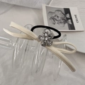 Dettaglio dell'elastico per capelli in raso crema con fiocco e fiore di cristallo lucido - Beige