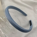 Detail of blue satin headband with a stitched Hand Made label on a smooth texture - Blue