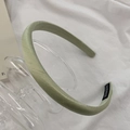 Detailed macro view of light green silk headband with a white handmade woven label - Pink