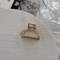 Detail of a minimalist gold alloy hair claw clip on a decorative stone surface - Semicircle Gold