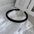 Detailaufnahme eines gepolsterten schwarzen Satin-Haarreifens auf weißem Papierhintergrund - Schwarz