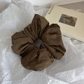 Detail of oversized dark coffee scrunchie on artistic paper with elegant matte texture - Brown