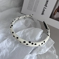 Detailansicht eines handgefertigten gepunkteten Haarreifens auf minimalistischem Magazin - Weißer Polka Dot