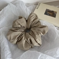 Detailed view of a khaki fabric scrunchie with pleated texture on a white background - Khaki