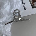 Detailaufnahme einer silbernen Herz-Haarklammer aus Metall auf einem Modemagazin - Silber