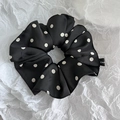Macro detail of black satin polka dot scrunchie with rich folds and designer woven label - Black White Polka Dot
