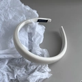 Detalle de diadema acolchada de satén crema hecha a mano con textura brillante y elegante - Blanco Leche