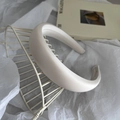 Detail eines beige gepolsterten Schwamm-Haarreifens mit Satin-Finish auf Metallständer - Beige