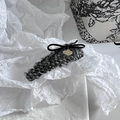 Detail van tweed haarklem met zwarte strik en gouden bedel in een vintage setting - Grijze Snap Clip