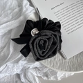 Elegante elastico in tweed nero e raso con perla metallica argentata su un piatto bianco - grigio scuro