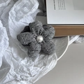 Detalle de coletero de flor de tweed gris con perla central en fondo elegante - Gris
