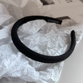 Detailed close-up of a black fabric headband with a Handmade woven label on white paper - Black