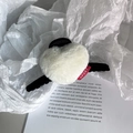 Detalle de pinza de pelo de corazón en felpa crema con etiqueta deportiva y base negra - Blanco