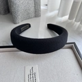 Close-up of thick black knitted headband with detailed fabric texture and gold label - Black
