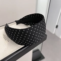 Cerchietto retrò in raso nero a pois bianchi su un espositore testurizzato elegante - Stile a Pois