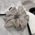 Dettaglio scrunchie in organza grigia con bordo argento ed etichetta su piatto bianco - Grigio