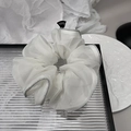 Detailed close-up of white organza scrunchie with silver edges and Fashion label - White