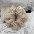 Close-up of champagne organza scrunchie with elegant white pearl details - Pink