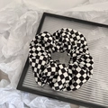 Vue détaillée d'un chouchou en tissu à carreaux noir et blanc sur un plateau en verre - Style Chouchou