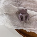 Close-up of small purple glossy hair claw clip on white paper and wooden tray - Purple