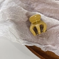 Macro shot of glossy mustard yellow mini hair claw clip on white textured paper - Yellow