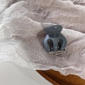 Macro shot of a dark gray glossy claw clip with three teeth on wrinkled tissue paper - Grey Blue