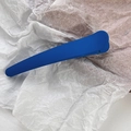 Macro detail of Klein blue matte hair clip on textured paper background for hairstyling - Klein Blue