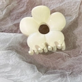 Close-up of cream white resin flower hair claw clip on soft grey textured paper - Milky White
