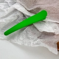 Close-up of bright green matte finish hair clip with long beak design on white paper - Green
