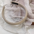 Close-up of a handmade cream fabric sponge headband with a black label on textured paper - Apricot