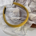 Detailed shot of yellow fabric headband featuring a handmade label on a white background - Turmeric