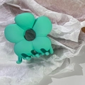 Details einer mintgrünen matten Blumenhaarklammer mit stabilen Zähnen auf Papier - Grün