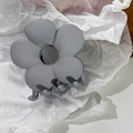 Nahaufnahme der matten, staubblauen Blumen-Haarklammer mit Textur und 3D-Design - Grau