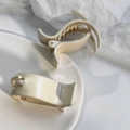 Detalle de pinzas para el cabello color crema en un entorno estético minimalista - Blanco Leche