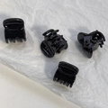 Detailed macro view of four mini black plastic hair clips with metal springs - Black