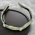Detail of light green satin headband with pearl clusters on a wooden tray background - Green