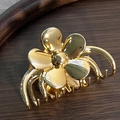 Dettaglio macro di un fermaglio per capelli a fiore dorato con finitura metallica lucida - Oro