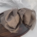 Dettaglio di un fermaglio per capelli in organza marrone con fiocco a strati su vassoio - Cioccolato
