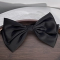 Close-up of a large black silk satin double bow hair clip on a wooden display tray - Black