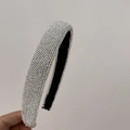 Close-up of wide sparkling rhinestone headband with shiny crystals and black lining - White