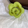 Nahaufnahme der mattgrünen Blumenhaarklammer mit Spiralmitte auf Holztablett - Wolkenstil