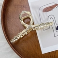 Dettaglio di grande molletta dorata a spirale con perle bianche e strass scintillanti - Incrocio Strass Perla