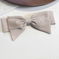 Dettaglio del fermaglio a fiocco in raso oro champagne con trama di tessuto elegante - Albicocca Cammello