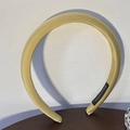 Detail of handmade padded ginger yellow satin headband on wooden desk - Turmeric