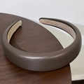 Gros plan du serre-tête épais en cuir PU marron montrant sa texture et sa doublure douce - café