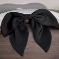 Elegant black satin bow hair clip with a smooth glossy finish on dark wooden tray - Black Bow
