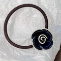 Detail eines hochelastischen Haargummis mit glänzend schwarz-weißer Kamelienblüte - Marineblau