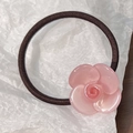 Detailed view of an elegant light pink camellia flower hair tie with glossy resin finish - Pink